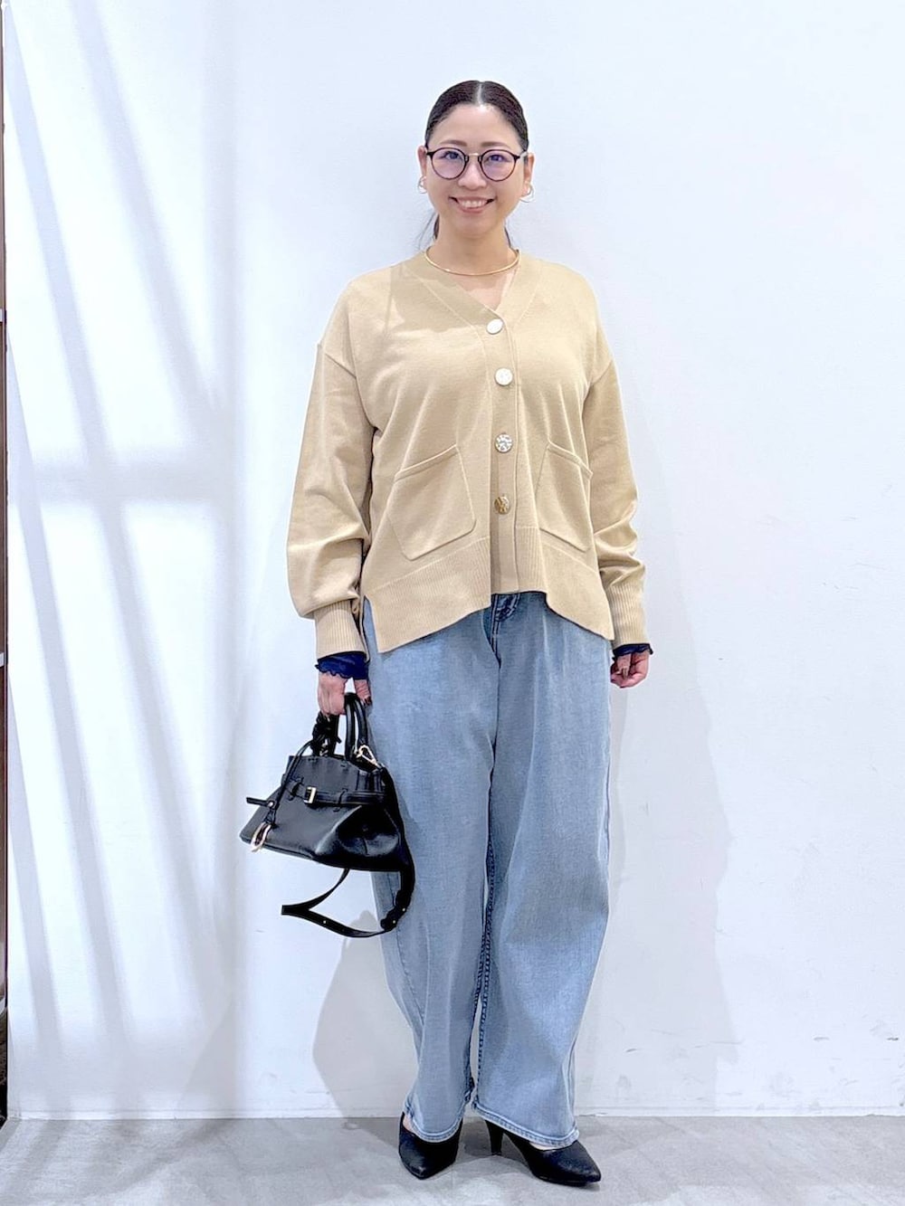 ブラック系のパンプス、ブルー系のデニムパンツ、ゴールド系のネックレスを着用したレディースの冬コーディネートの2枚目の写真