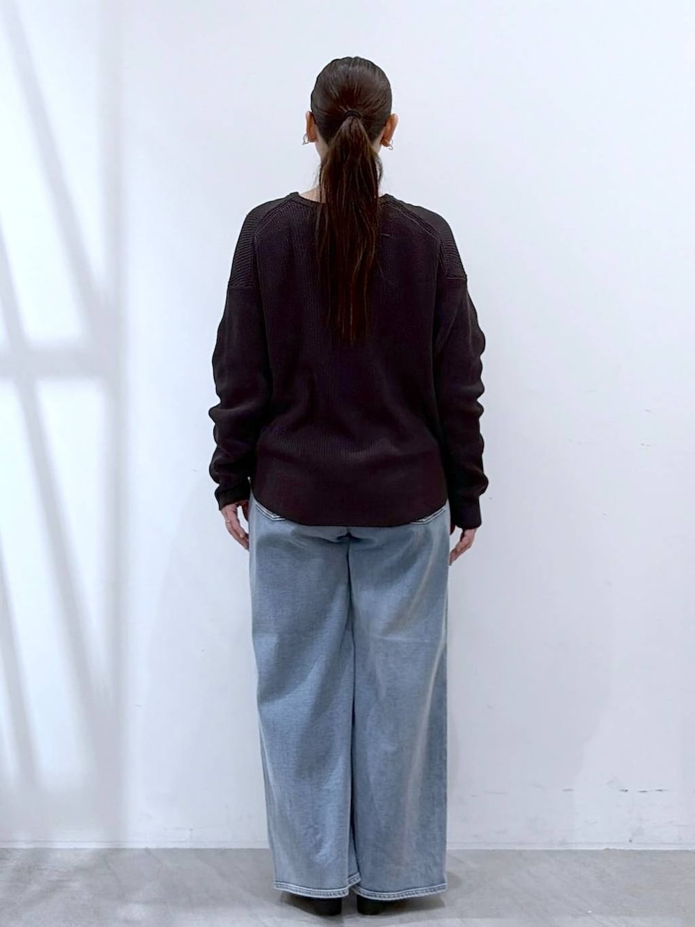 ホワイト系のタンクトップ、ブルー系のデニムパンツ、ブラック系のパンプスを着用したレディースの春コーディネートの4枚目の写真