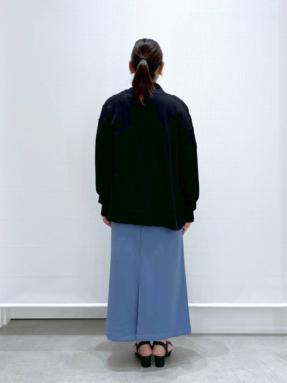 ブラック系のサンダル、ホワイト系のTシャツ/カットソー、ブルー系のスカートを着用したレディースの秋コーディネートの4枚目の写真