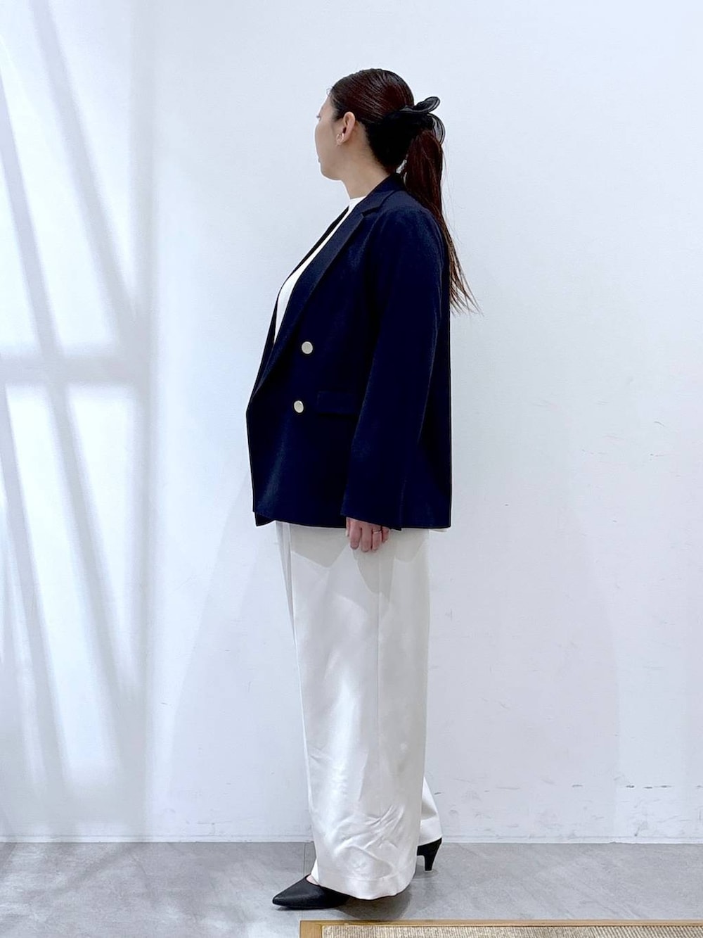 ホワイト系のスラックス、ホワイト系のシャツ/ブラウス、ブラック系のハンドバッグを着用したレディースの冬コーディネートの3枚目の写真