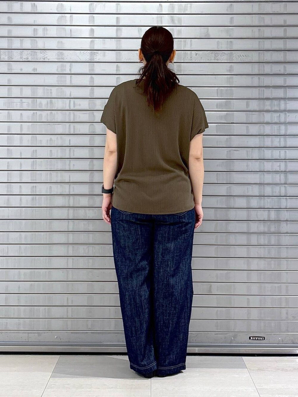 ブルー系のデニムパンツ、ブラック系のハンドバッグ、グリーン系のTシャツ/カットソーを着用したレディースの春コーディネートの4枚目の写真