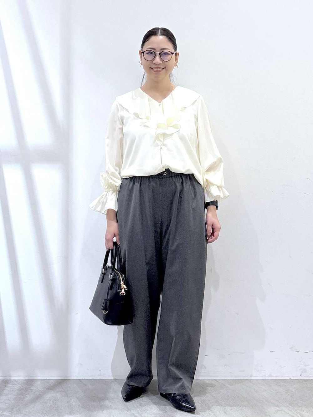 ブラック系のパンプス、ブルー系のカーディガン/ボレロ、ブラック系のハンドバッグを着用したレディースの冬コーディネートの2枚目の写真