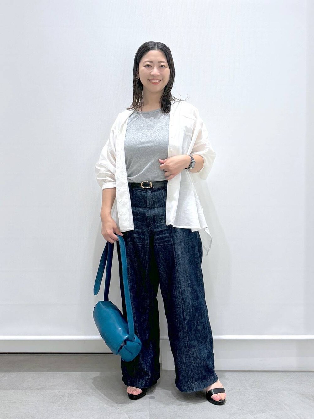 ブルー系のデニムパンツ、ホワイト系のTシャツ/カットソー、ブラック系のサンダルを着用したレディースの夏コーディネートの2枚目の写真