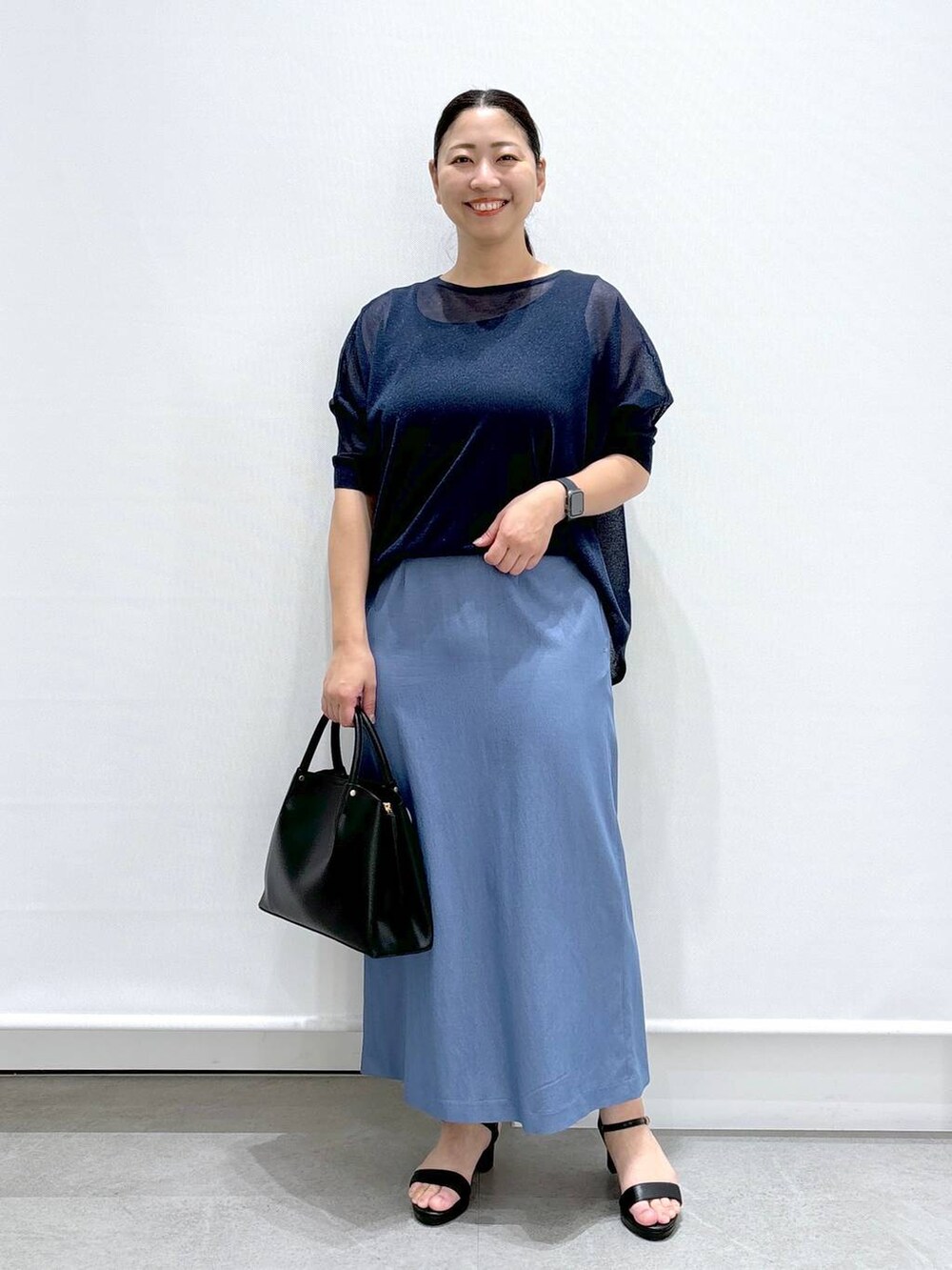 ブラック系のショルダーバッグ、ブラック系のサンダル、ブルー系のニット/セーターを着用したレディースの夏コーディネートの2枚目の写真