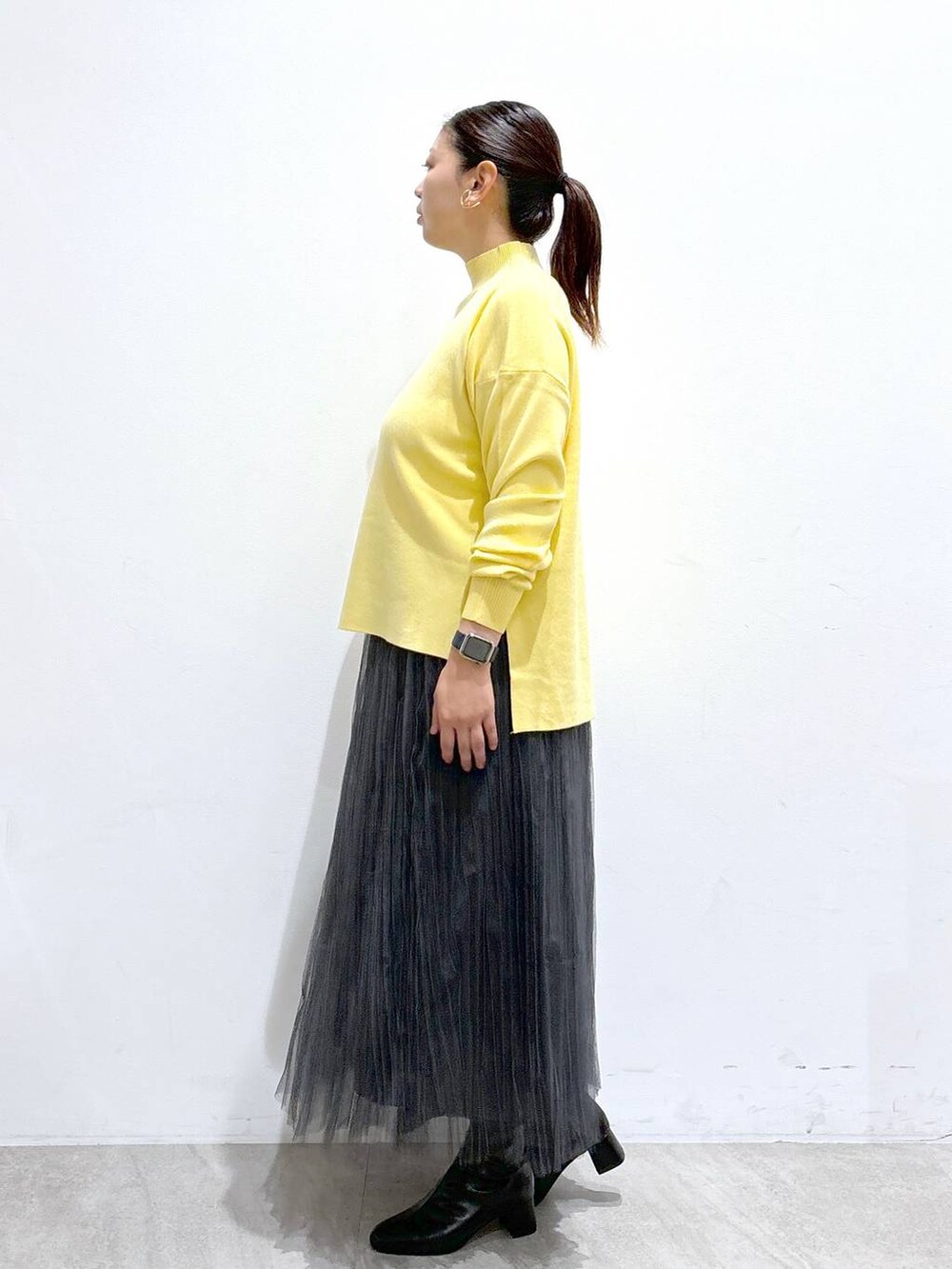 ブラック系のハンドバッグ、グレー系のスカート、ブラック系のブーツを着用したレディースの秋コーディネートの3枚目の写真