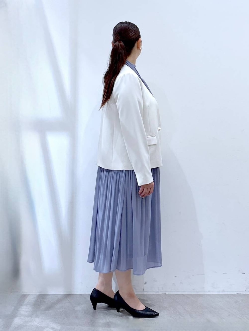 ブラック系のハンドバッグ、ホワイト系のノーカラージャケット、ブルー系のワンピースを着用したレディースの冬コーディネートの5枚目の写真