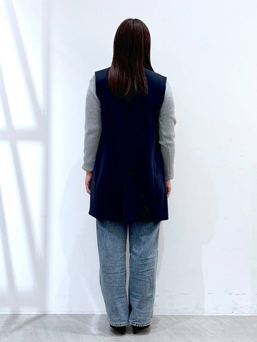 ブルー系のデニムパンツ、グレー系のニット/セーター、ブルー系のスーツベストを着用したレディースの冬コーディネートの4枚目の写真