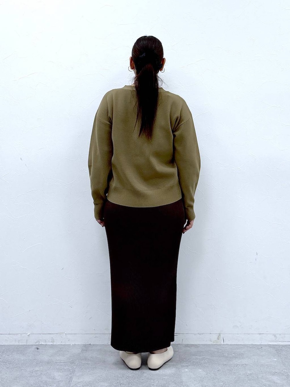 ホワイト系のパンプス、ホワイト系のハンドバッグ、イエロー系のカーディガン/ボレロを着用したレディースの冬コーディネートの4枚目の写真