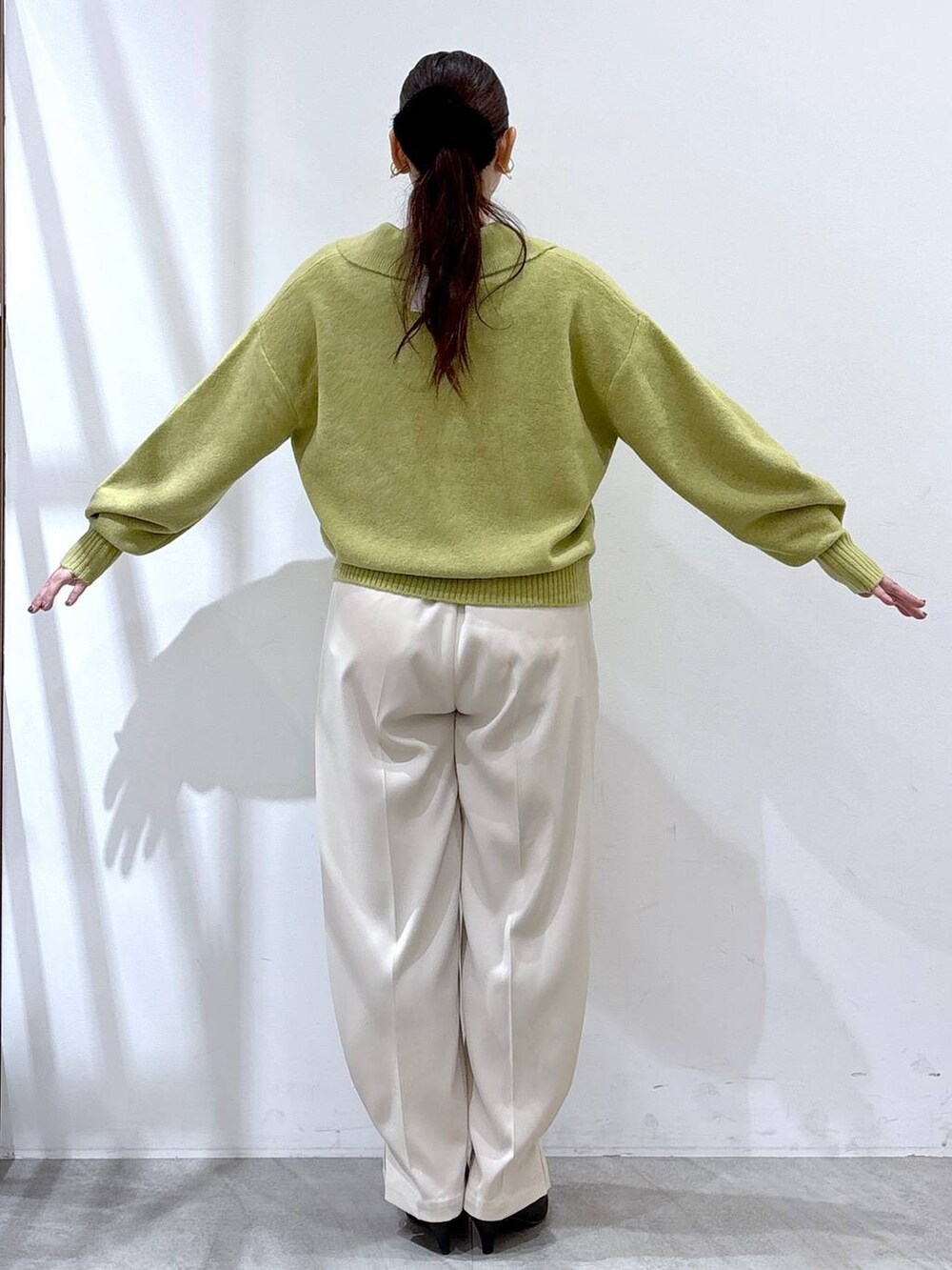 ブラック系のパンプス、ホワイト系のその他パンツ、イエロー系のニット/セーターを着用したレディースの冬コーディネートの5枚目の写真