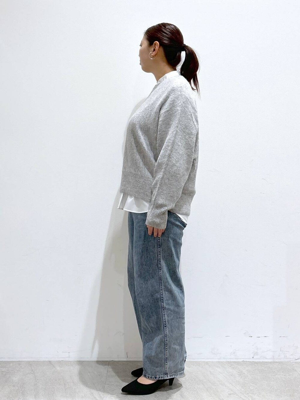 ブルー系のデニムパンツ、ホワイト系のシャツ/ブラウス、グレー系のニット/セーターを着用したレディースの冬コーディネートの3枚目の写真