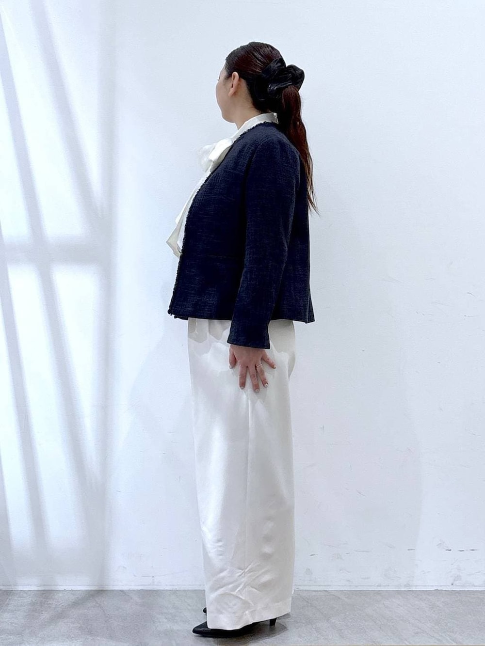 ブルー系のノーカラージャケット、ホワイト系のスラックス、ホワイト系のシャツ/ブラウスを着用したレディースの冬コーディネートの3枚目の写真
