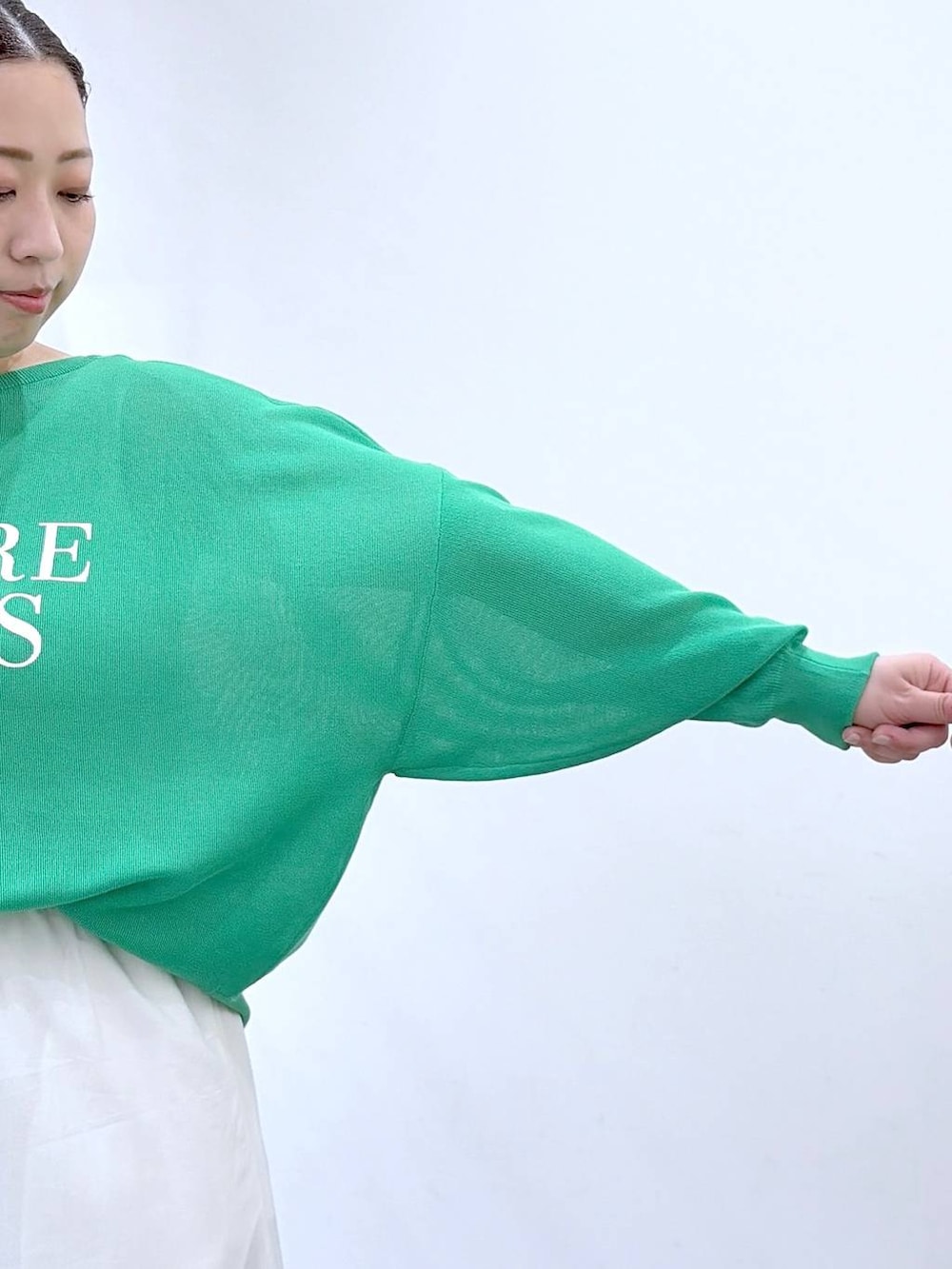 ブラック系のトートバッグ、ホワイト系のスカート、グリーン系のカーディガン/ボレロを着用したレディースの春コーディネートの6枚目の写真