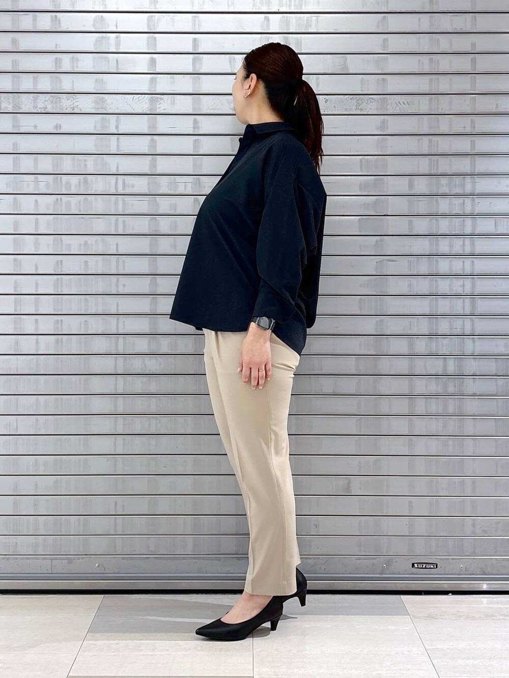 ブラック系のパンプス、ブルー系のシャツ/ブラウス、ブラック系のハンドバッグを着用したレディースの春コーディネートの3枚目の写真