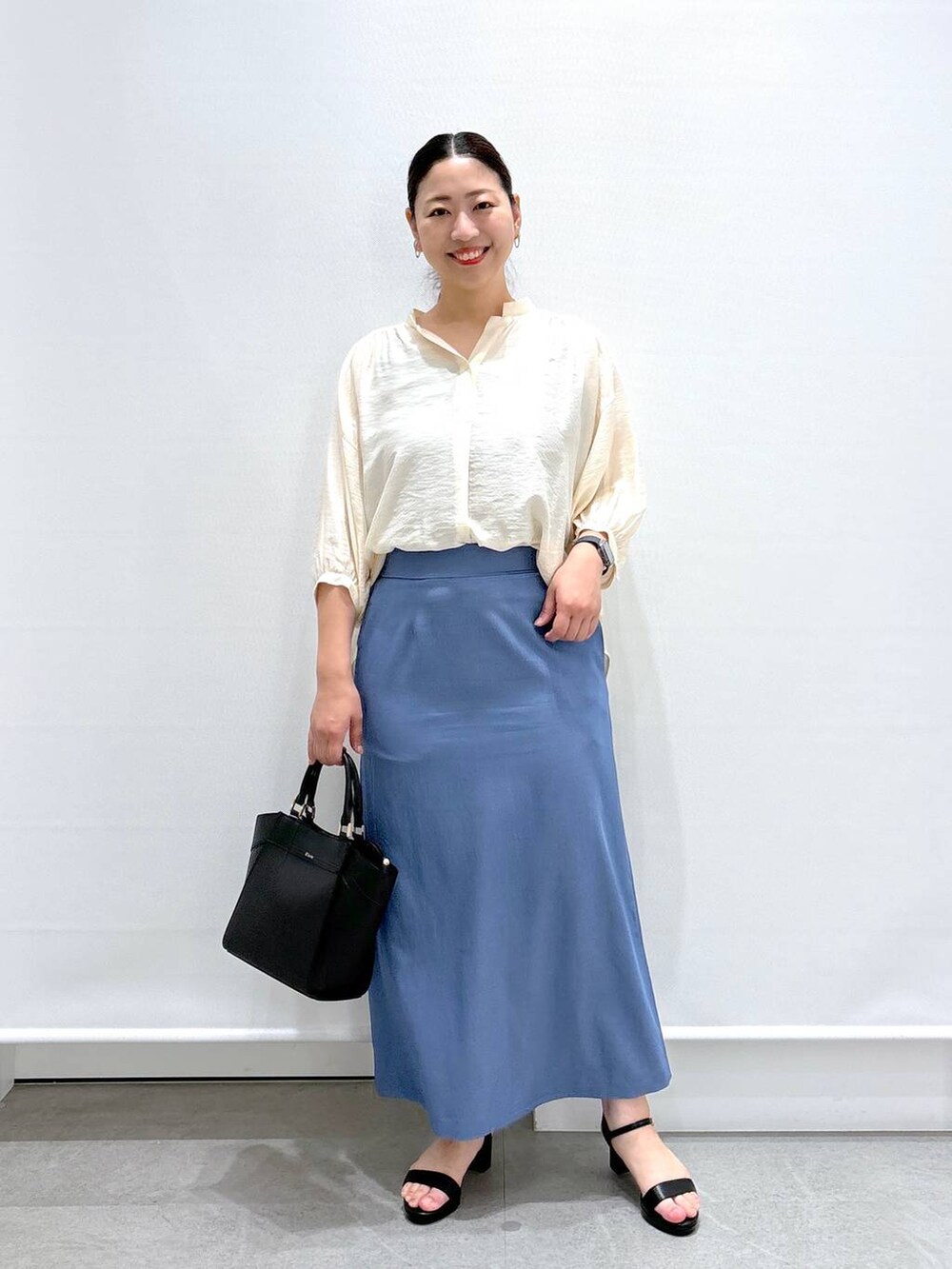 ホワイト系のシャツ/ブラウス、ブラック系のサンダル、ブラック系のハンドバッグを着用したレディースの夏コーディネートの2枚目の写真