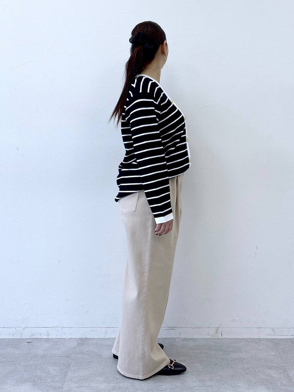 ブラック系のハンドバッグ、ベージュ系のデニムパンツ、ブラック系のカーディガン/ボレロを着用したレディースの冬コーディネートの5枚目の写真