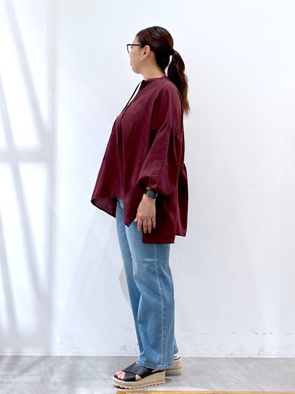 ブラック系のハンドバッグ、ブラック系のサンダル、ブルー系のデニムパンツを着用したレディースの夏コーディネートの2枚目の写真