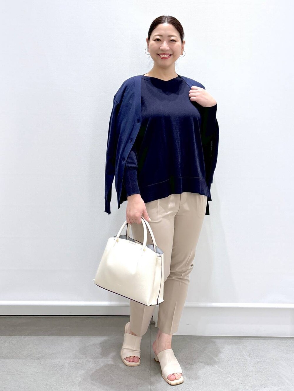 ベージュ系のその他パンツ、ホワイト系のショルダーバッグ、ブルー系のニット/セーターを着用したレディースの春コーディネートの2枚目の写真