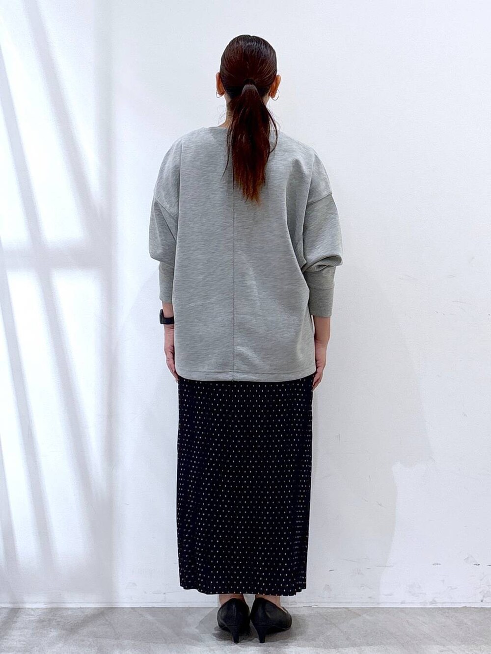 ブラック系のパンプス、グレー系のTシャツ/カットソー、ブラック系のスカートを着用したレディースの秋コーディネートの3枚目の写真