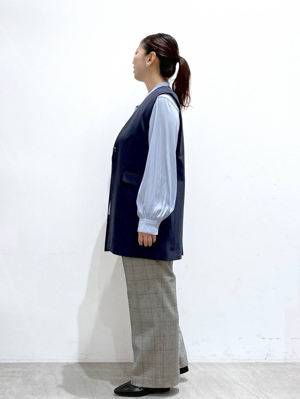 ブルー系のベスト、ブラック系のハンドバッグ、ブルー系のシャツ/ブラウスを着用したレディースの秋コーディネートの3枚目の写真