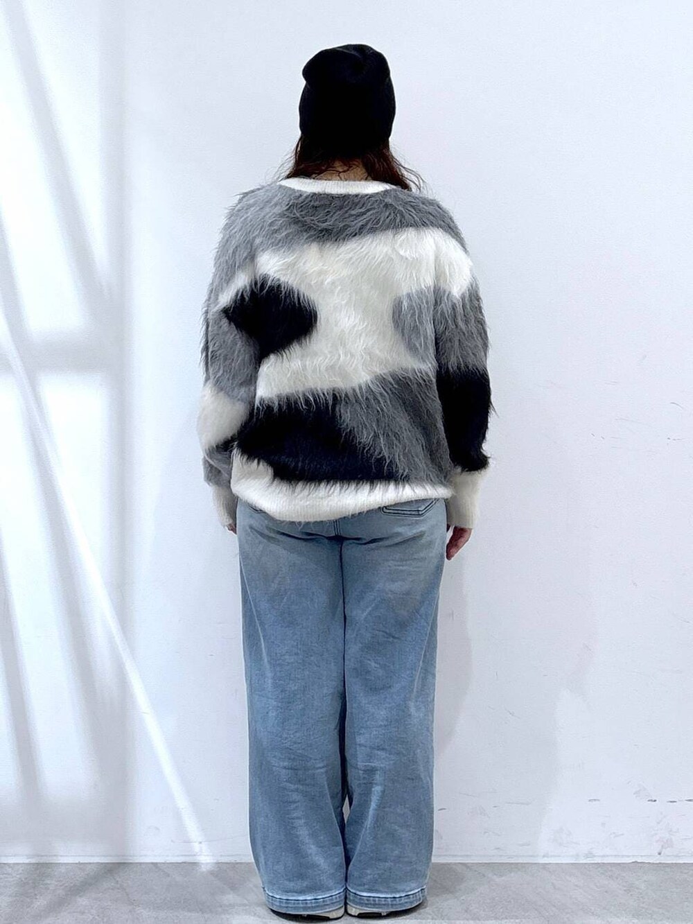 ブラック系のショルダーバッグ、ブルー系のデニムパンツ、ホワイト系のニット/セーターを着用したレディースの冬コーディネートの3枚目の写真