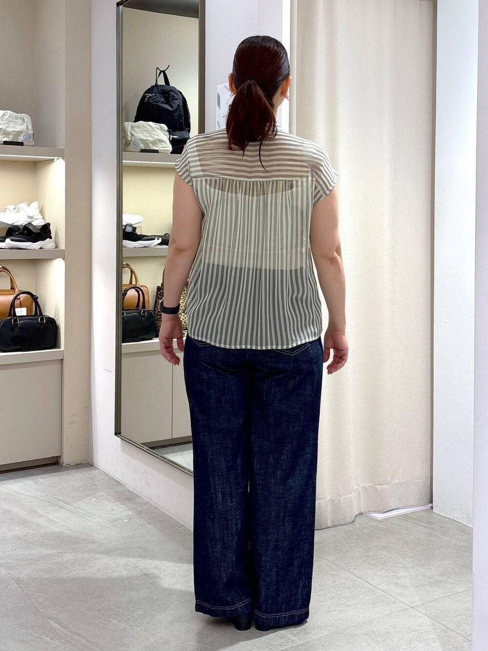 グレー系のシャツ/ブラウス、ブルー系のデニムパンツ、ブラック系のハンドバッグを着用したレディースの夏コーディネートの3枚目の写真