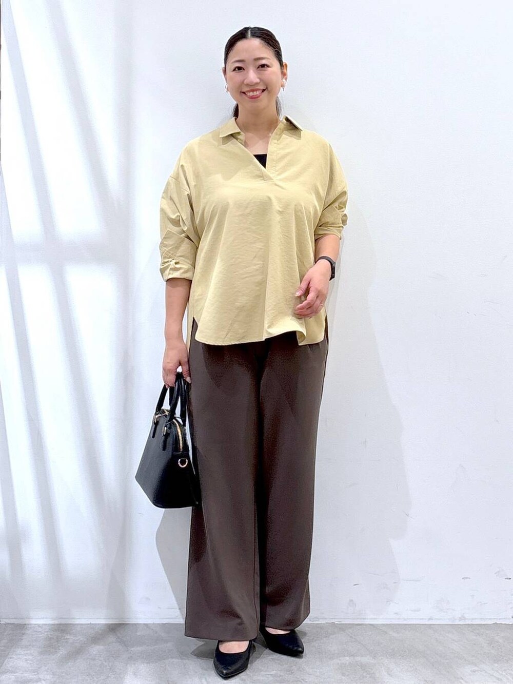 ブラック系のパンプス、イエロー系のシャツ/ブラウス、ブラック系のハンドバッグを着用したレディースの秋コーディネートの2枚目の写真