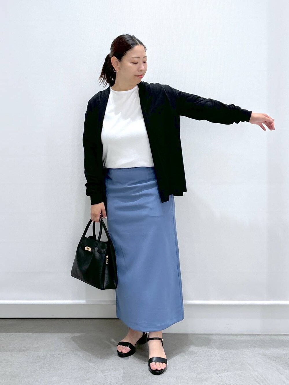 ブラック系のサンダル、ホワイト系のTシャツ/カットソー、ブルー系のスカートを着用したレディースの秋コーディネートの2枚目の写真