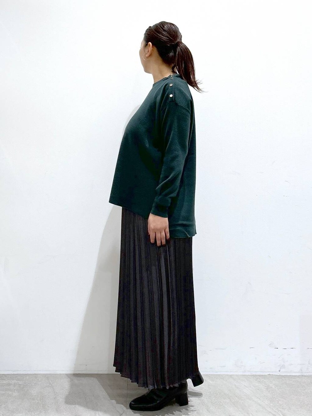 ブラック系のブーツ、グリーン系のニット/セーター、グレー系のスカートを着用したレディースの秋コーディネートの3枚目の写真