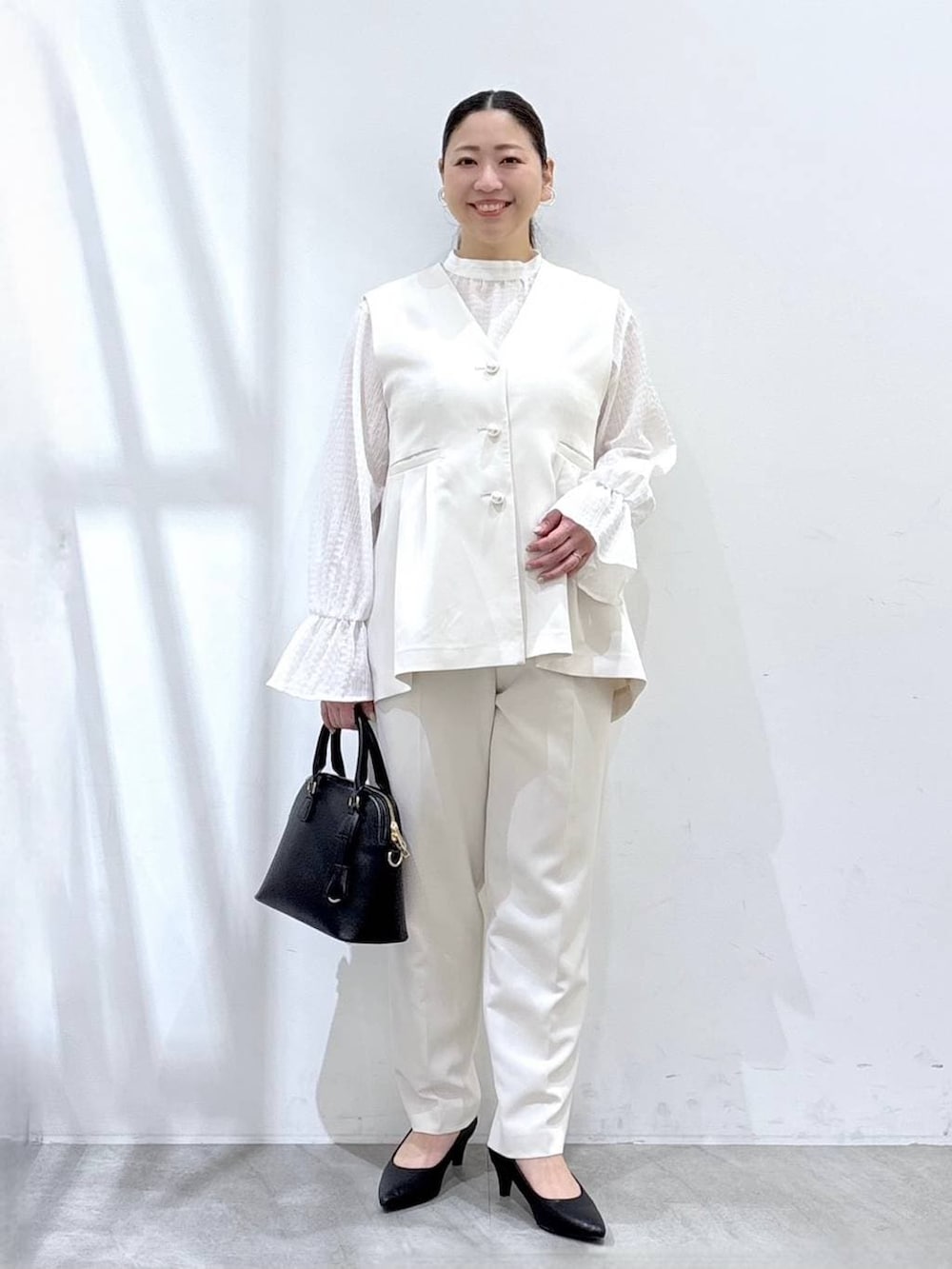 ブラック系のハンドバッグ、ホワイト系のシャツ/ブラウス、ホワイト系のベストを着用したレディースの冬コーディネートの2枚目の写真