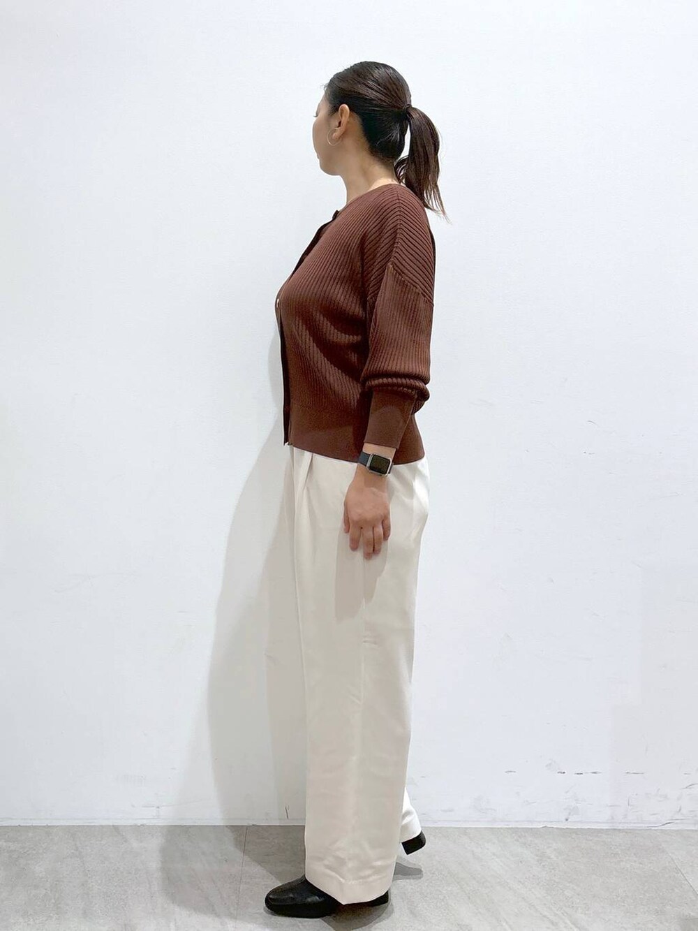 ブラウン系のカーディガン/ボレロ、ブラック系のブーツ、ブラウン系のハンドバッグを着用したレディースの秋コーディネートの3枚目の写真