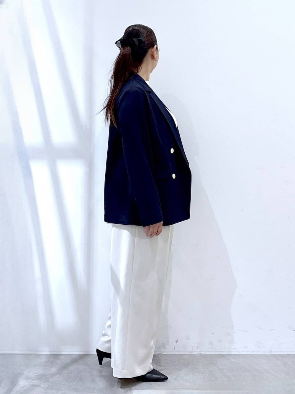 ホワイト系のスラックス、ホワイト系のシャツ/ブラウス、ブラック系のハンドバッグを着用したレディースの冬コーディネートの5枚目の写真