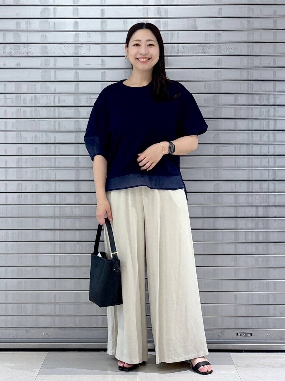 ブラック系のハンドバッグ、ブルー系のTシャツ/カットソー、ベージュ系のその他パンツを着用したレディースの春コーディネートの2枚目の写真