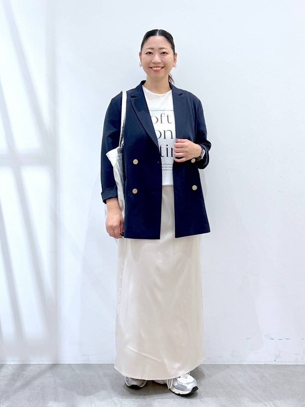 グレー系のスニーカー、シルバー系のトートバッグ、ホワイト系のTシャツ/カットソーを着用したレディースの秋コーディネートの2枚目の写真