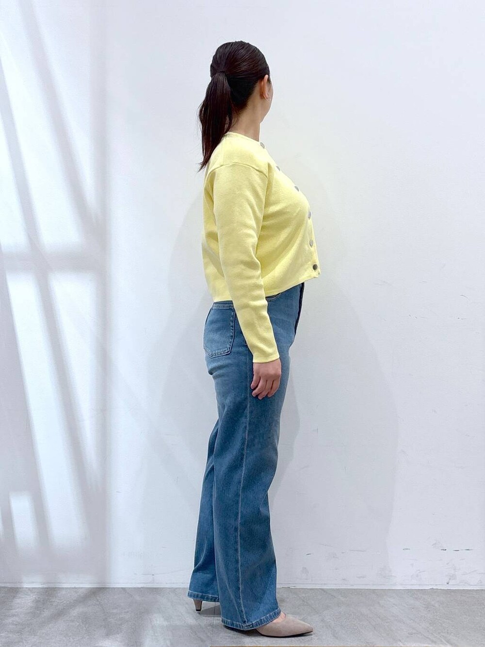 ベージュ系のパンプス、ブルー系のデニムパンツ、イエロー系のカーディガン/ボレロを着用したレディースの冬コーディネートの5枚目の写真