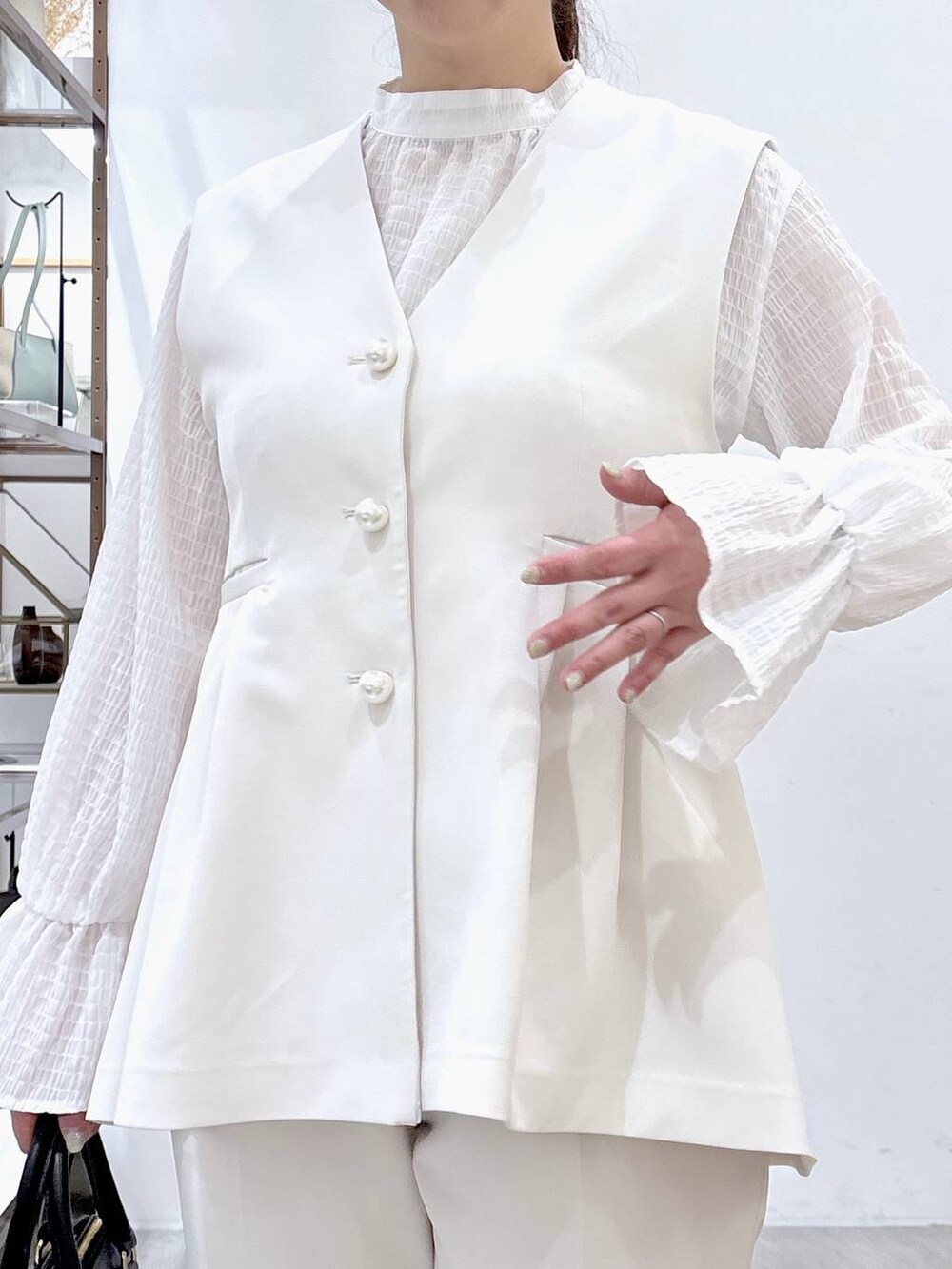 ブラック系のハンドバッグ、ホワイト系のシャツ/ブラウス、ホワイト系のベストを着用したレディースの冬コーディネートの7枚目の写真