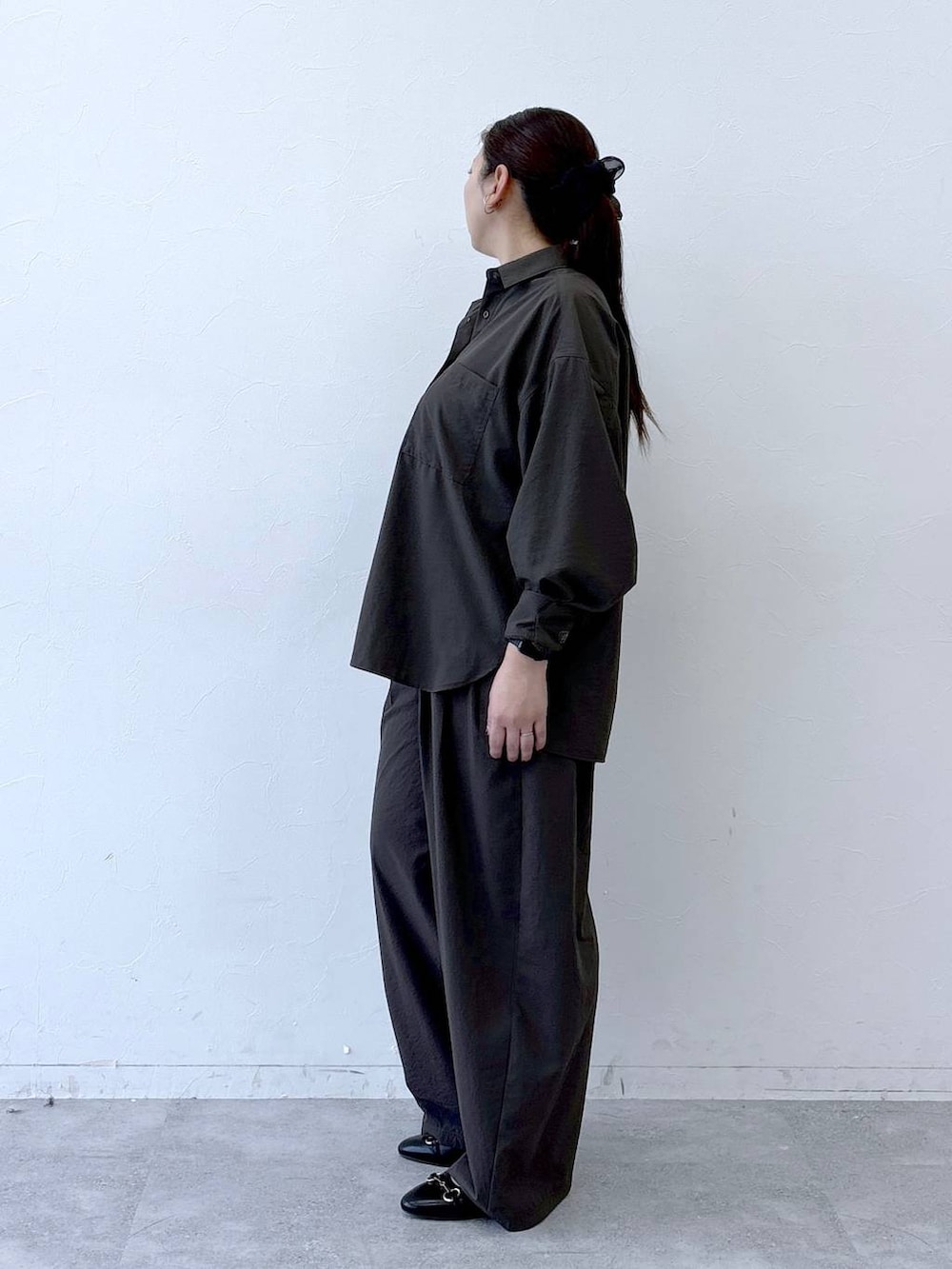 ブラック系のハンドバッグ、ブラック系のパンプス、ブラウン系のシャツ/ブラウスを着用したレディースの冬コーディネートの2枚目の写真