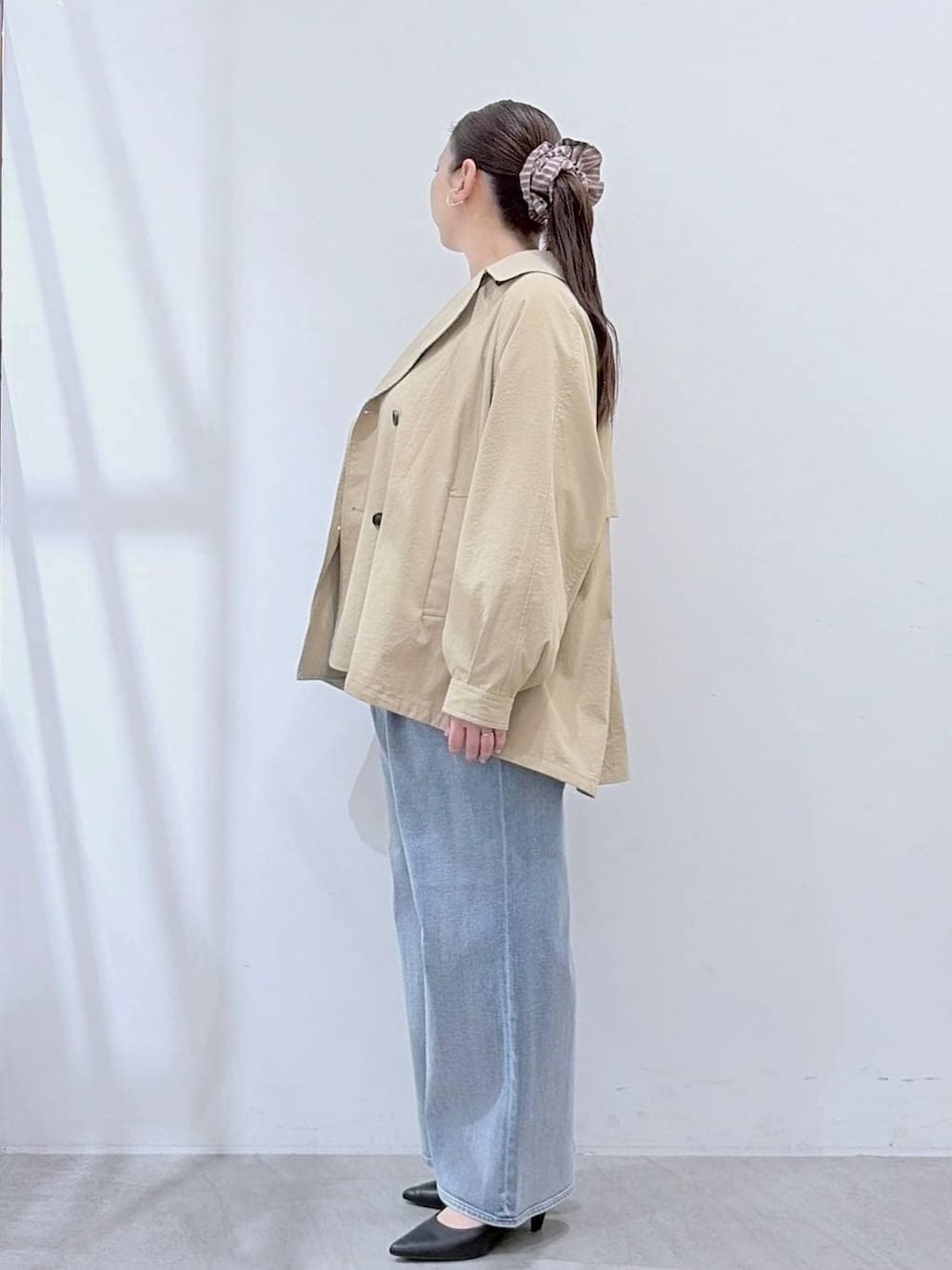 ホワイト系のニット/セーター、ブルー系のデニムパンツ、ブラック系のハンドバッグを着用したレディースの春コーディネートの3枚目の写真