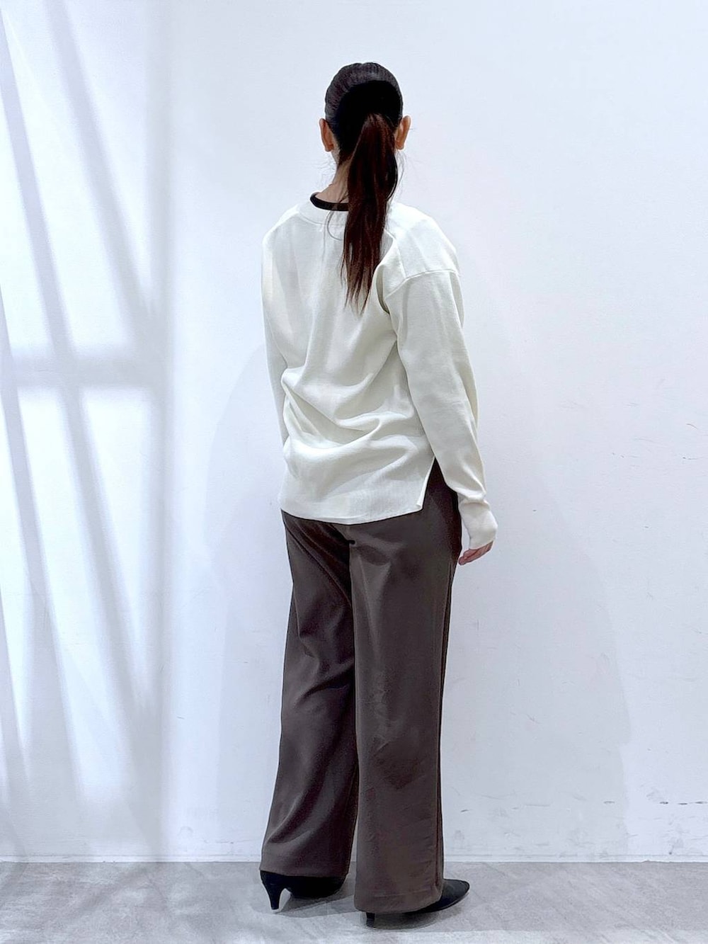 ホワイト系のカーディガン/ボレロ、ブラウン系のその他パンツ、ブラック系のハンドバッグを着用したレディースの冬コーディネートの5枚目の写真