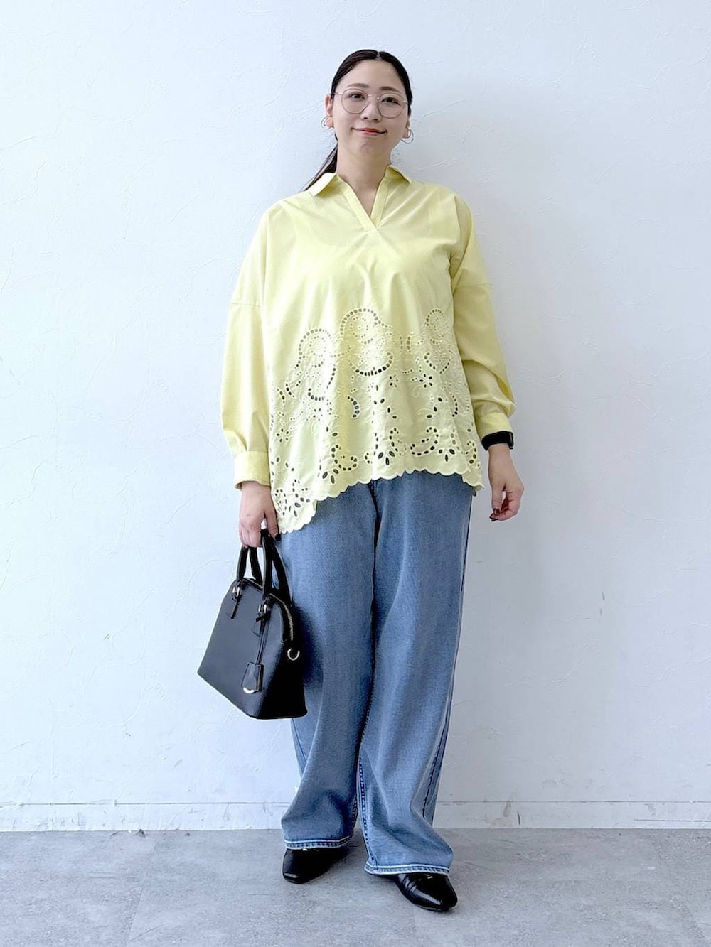 ブラック系のハンドバッグ、ブラック系のパンプス、ブルー系のデニムパンツを着用したレディースの冬コーディネートの2枚目の写真