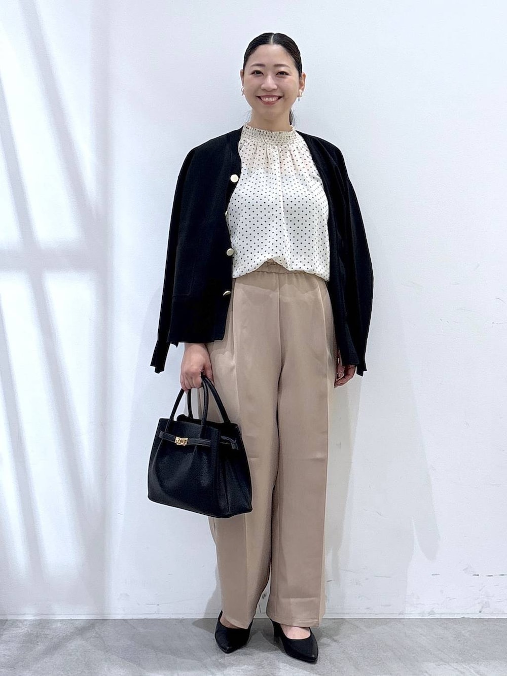 ブラック系のパンプス、ブラック系のカーディガン/ボレロ、ブラック系のハンドバッグを着用したレディースの秋コーディネートの2枚目の写真