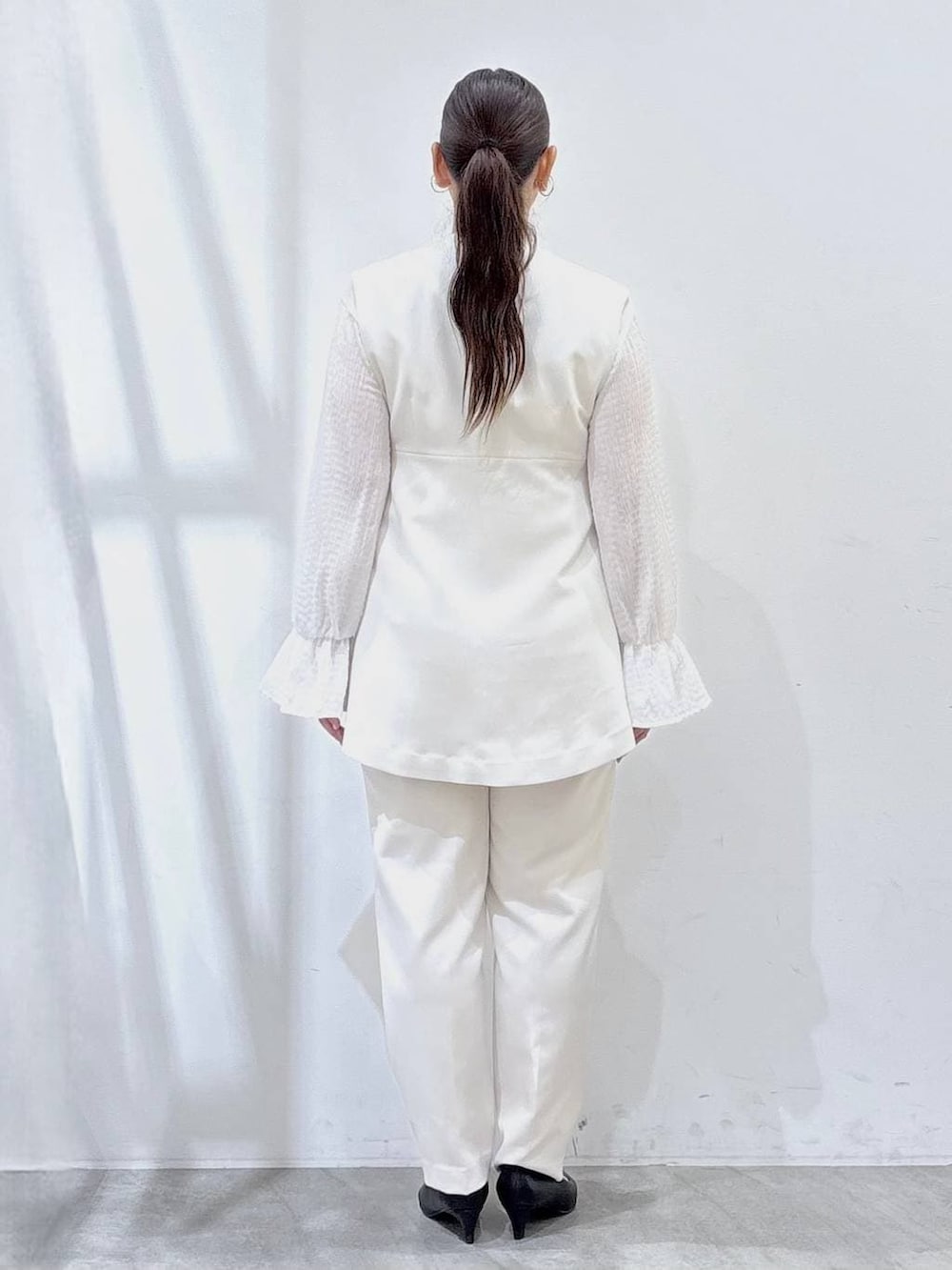 ブラック系のハンドバッグ、ホワイト系のシャツ/ブラウス、ホワイト系のベストを着用したレディースの冬コーディネートの4枚目の写真