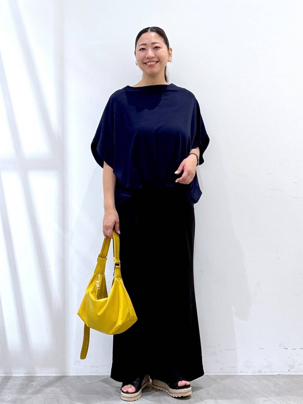 ブラック系のその他パンツ、イエロー系のハンドバッグ、ブルー系のTシャツ/カットソーを着用したレディースの夏コーディネートの2枚目の写真