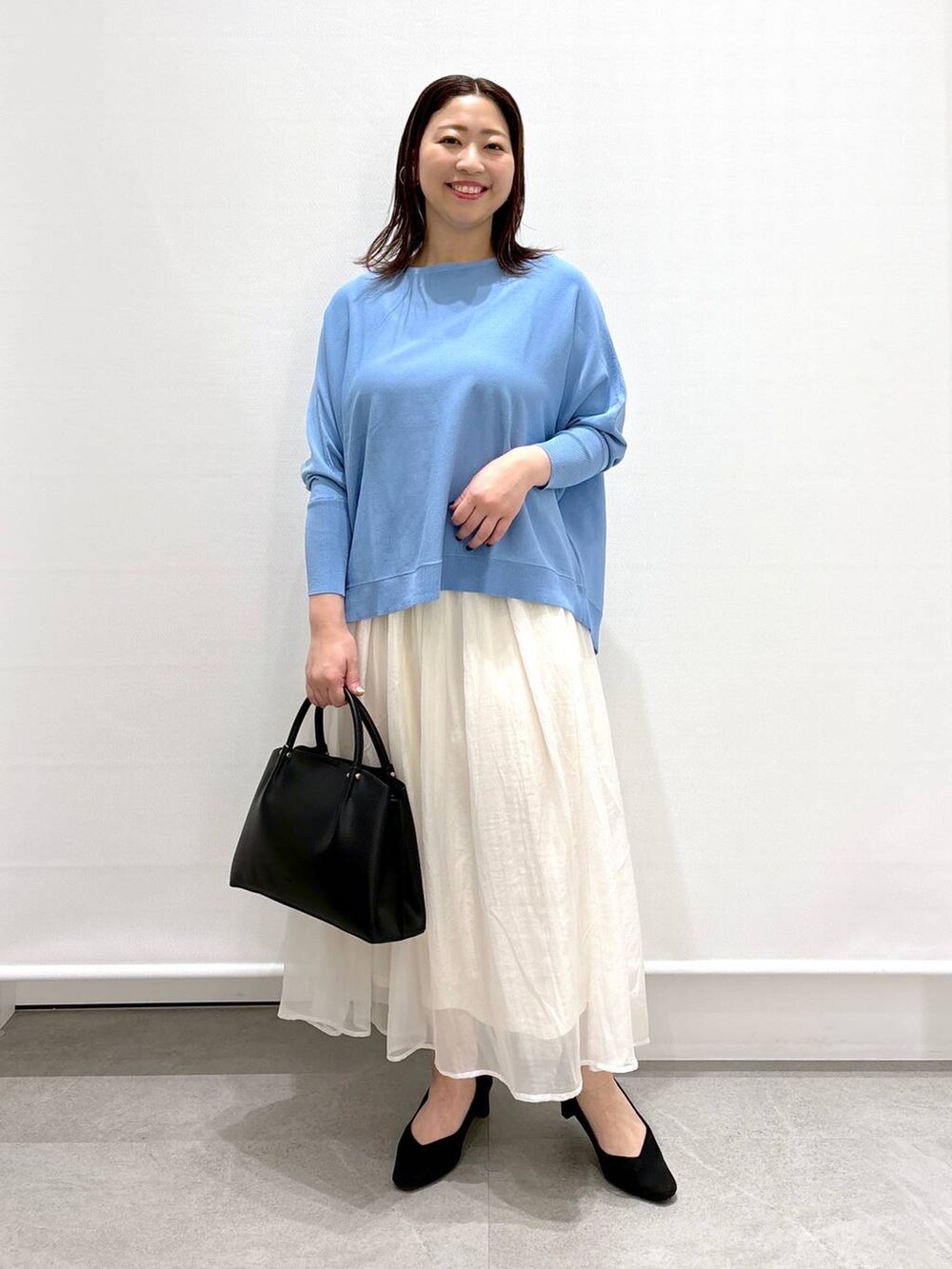 ホワイト系のスカート、ブラック系のショルダーバッグ、ブラック系のパンプスを着用したレディースの春コーディネートの2枚目の写真