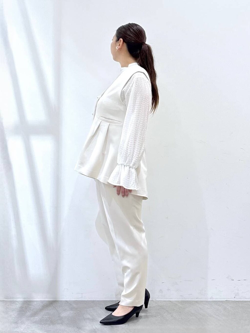 ブラック系のハンドバッグ、ホワイト系のシャツ/ブラウス、ホワイト系のベストを着用したレディースの冬コーディネートの3枚目の写真