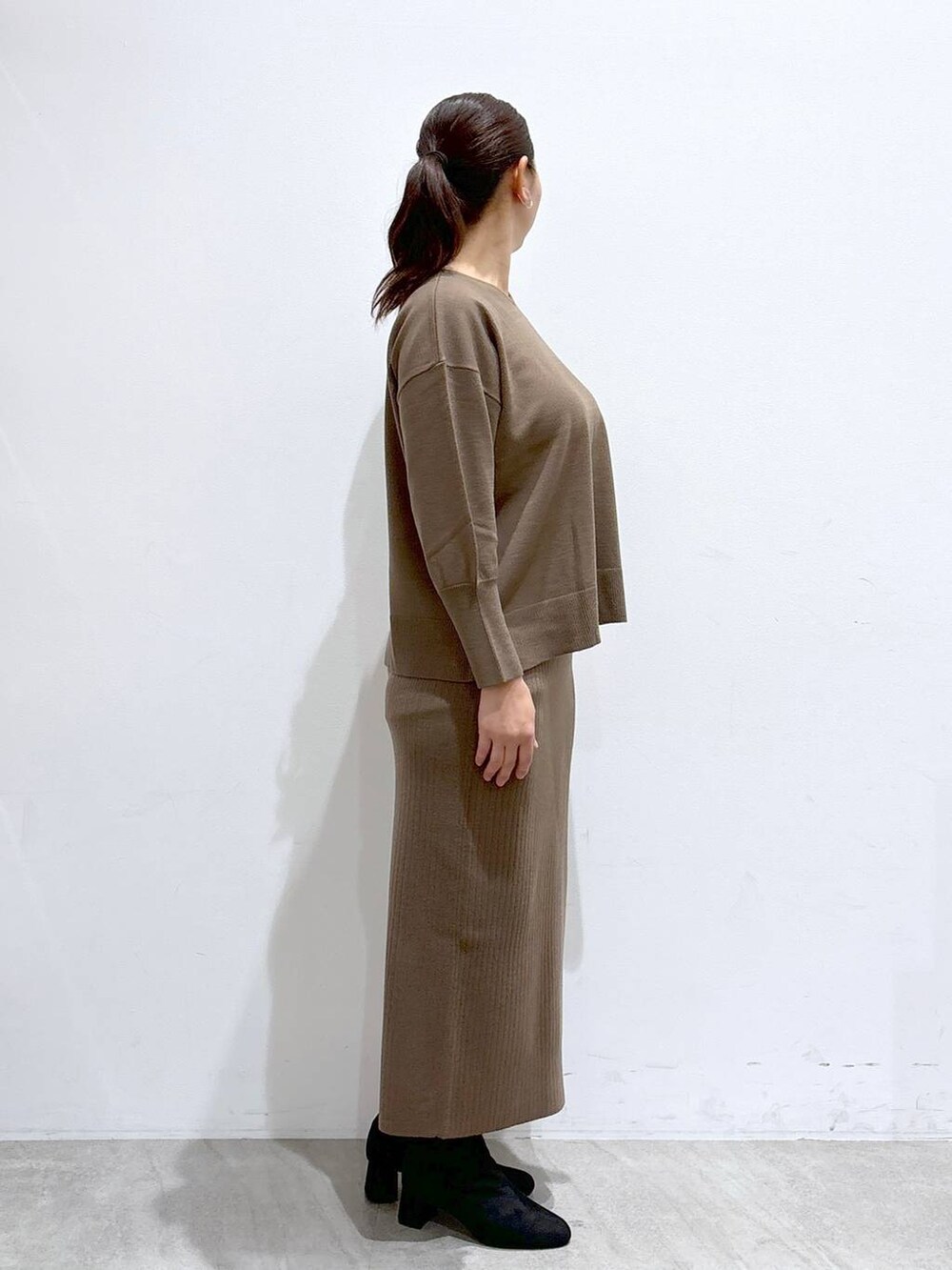 グレー系のブーツ、ブラック系のハンドバッグ、ホワイト系のその他アウターを着用したレディースの冬コーディネートの5枚目の写真