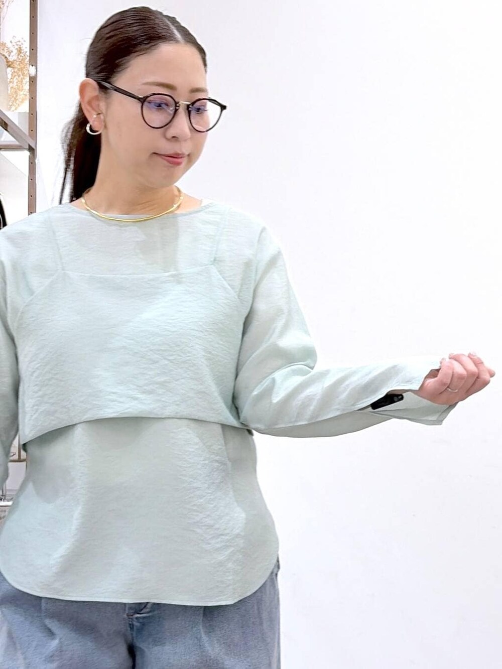 ブルー系のデニムパンツ、ブラック系のハンドバッグ、グリーン系のシャツ/ブラウスを着用したレディースの春コーディネートの6枚目の写真