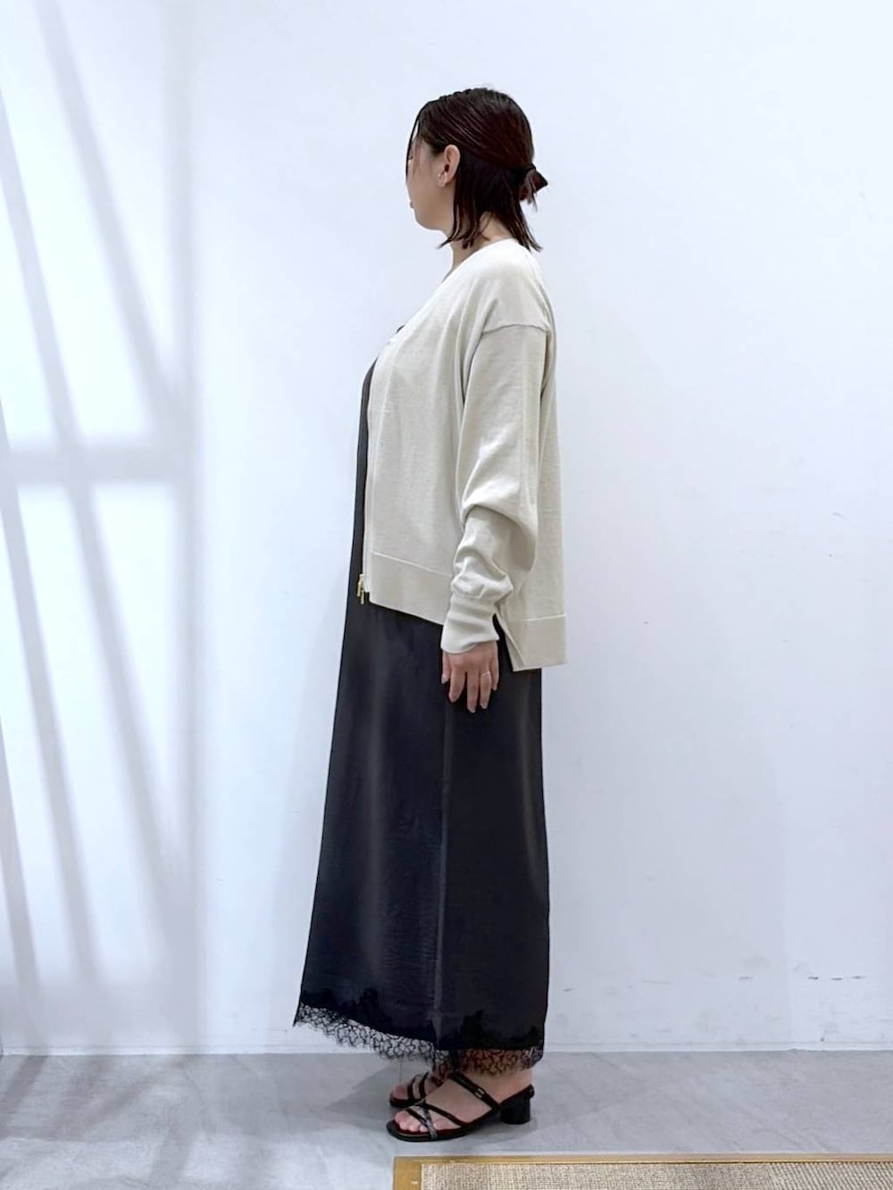ベージュ系のカーディガン/ボレロ、グレー系のワンピース、ブラック系のサンダルを着用したレディースの秋コーディネートの3枚目の写真
