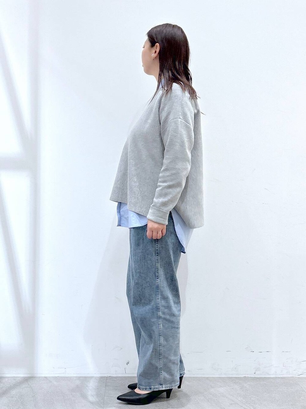 ブルー系のデニムパンツ、ブラック系のハンドバッグ、グレー系のニット/セーターを着用したレディースの冬コーディネートの3枚目の写真