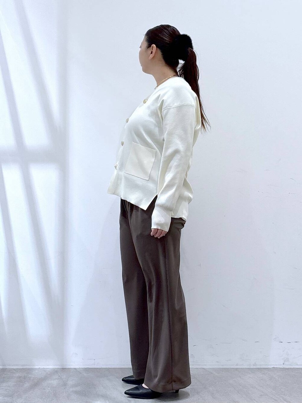 ホワイト系のカーディガン/ボレロ、ブラウン系のその他パンツ、ブラック系のハンドバッグを着用したレディースの冬コーディネートの3枚目の写真