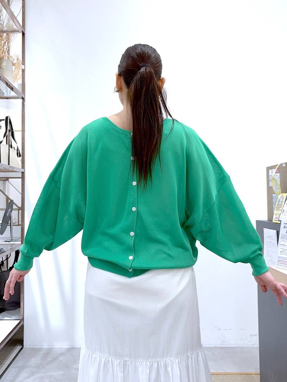 ブラック系のトートバッグ、ホワイト系のスカート、グリーン系のカーディガン/ボレロを着用したレディースの春コーディネートの8枚目の写真